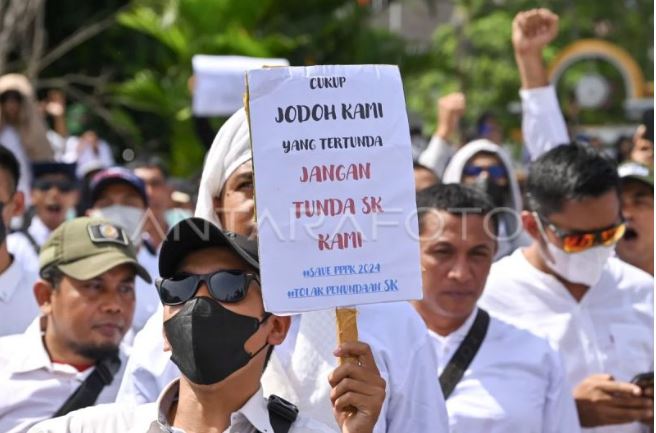 Menata Ulang Harapan Honorer di Tengah Krisis Fiskal Arsip - Pengunjuk rasa yang tergabung dalam Forum Aliansi Calon Pegawai Pemerintah dengan Perjanjian Kerja (PPPK) NTB Tahun 2024 memegang poster saat mengikuti aksi damai di kantor DPRD NTB di Mataram, NTB, Senin (10/3/2025). Ribuan Calon Pegawai Pemerintah dengan Perjanjian Kerja (PPPK) NTB tahun 2024 tersebut melakukan aksi damai penolakan penundaan pengangkatan CASN dan PPPK Tahun 2024. (Dok. Istimewa)